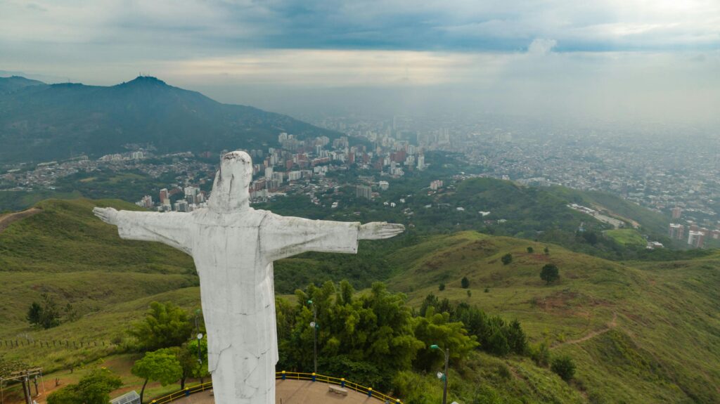 Aerial shot of Christ the Redeemer statue overlooking a cityscape and lush green hills.